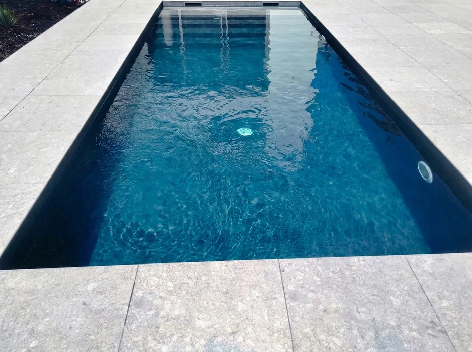 Piscine rectangulaire extérieure de type couloir de nage, revêtement intérieur en membrane dark graphite/anthracite, eau cristalline bleu profond