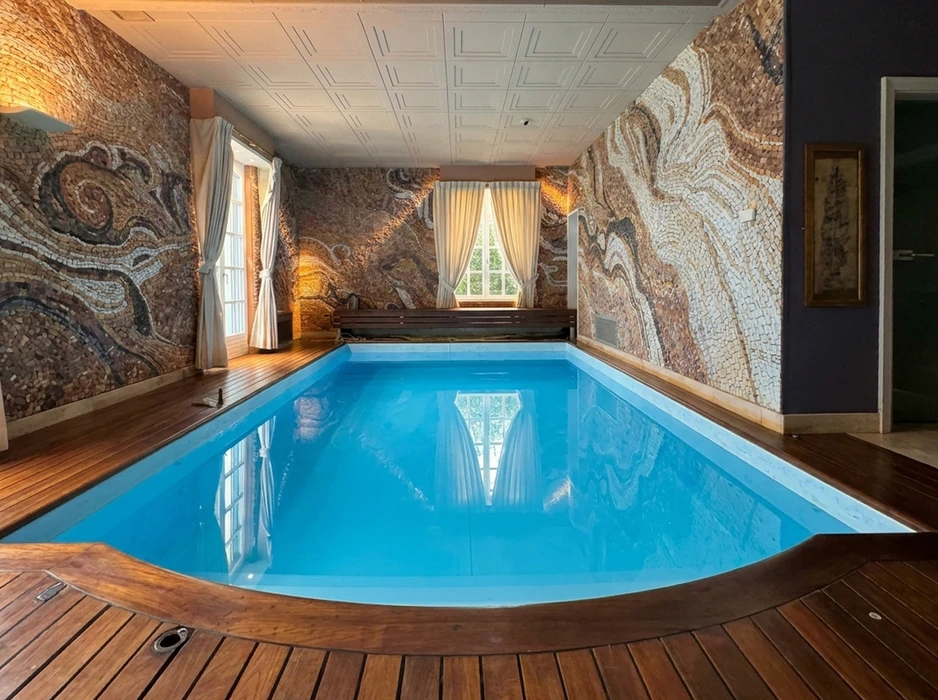 Piscine intérieure rectangulaire aux eaux turquoise, entourée d'un plancher en teck