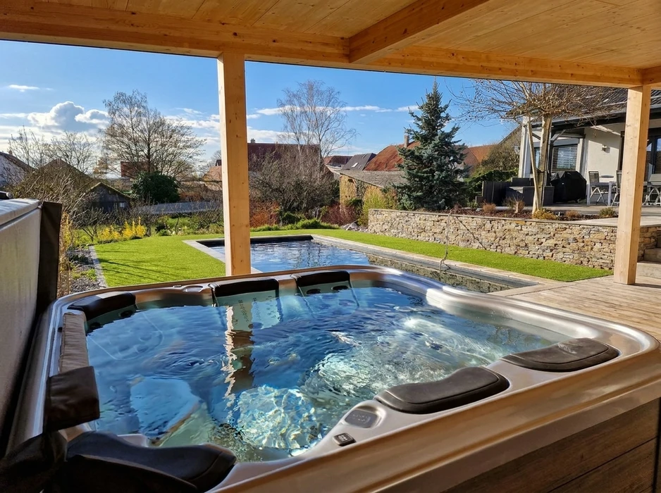 Chantier d'installation d'une piscine enterrée en coque polyester blanche, posée dans une fouille entre une maison et une clôture