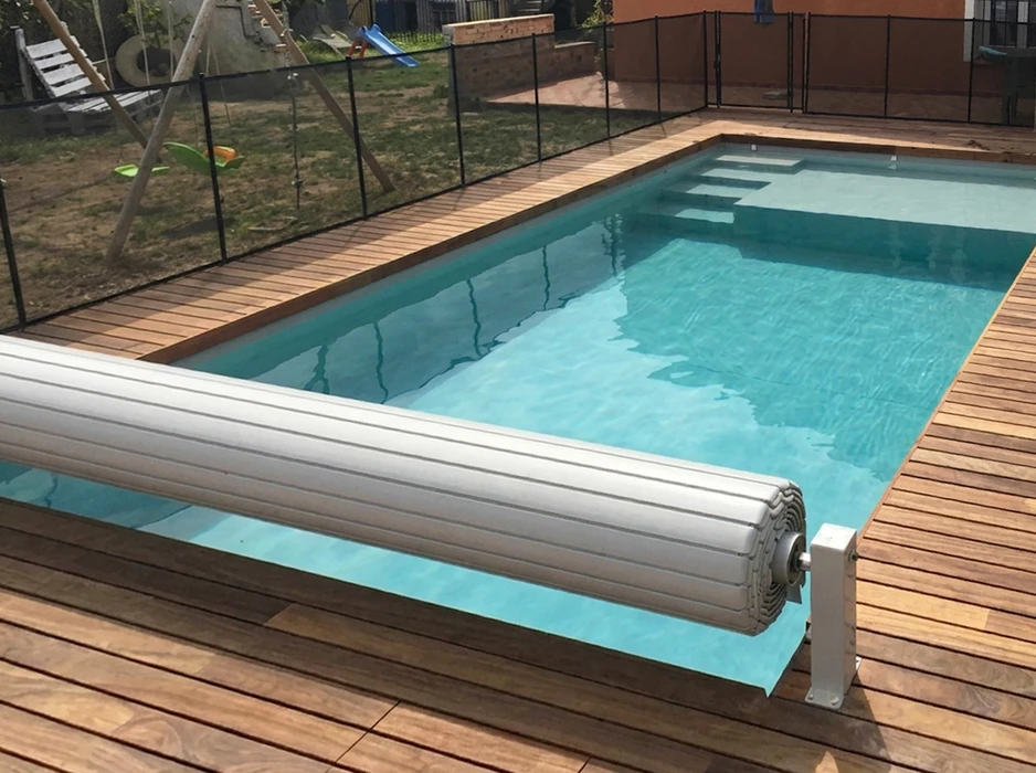 Chantier d'installation d'une piscine enterrée en coque polyester blanche, posée dans une fouille entre une maison et une clôture